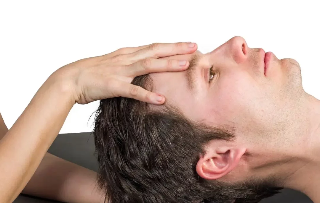 Une main en train de masser le crâne d'un homme